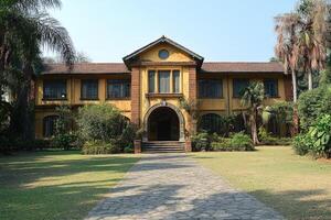 Elegant Yellow Colonial Style House Amidst Lush Greenery photo