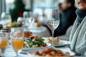 A Glass of Water on a Table with a Plate of Food and a Man in the Background photo