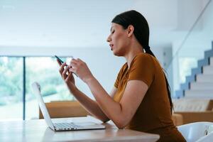 A woman sitting in the living room using a laptop and a smartphone look at camtalk by call with business friends and relatives, head shot. Job interview answering questions. photo