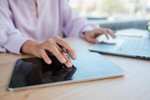 Hands interacting with a tablet and laptop on a wooden desk, showcasing modern technology use in a professional setting. photo