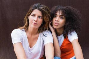 Calm diverse girlfriends listening to music with earphones on photo