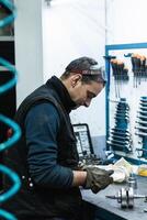 Professional mechanic using spanner while assembling vehicle. engine details at workbench photo