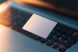 A blank business card hovers slightly above a laptop keyboard, beautifully illuminated by soft lighting. The modern workspace in the background exudes innovation and tech appeal photo