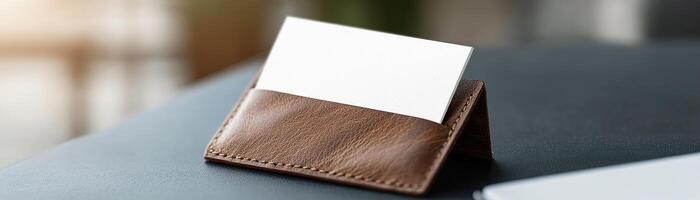 Blank business card is partially tucked into a high-quality leather cardholder. Soft lighting enhances the texture, creating an elegant atmosphere hinting at a corporate environment photo