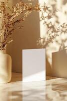 Blank business card stands upright against a neutral-toned wall. The soft focus and gentle reflections create an aesthetic backdrop, ideal for luxury branding applications photo