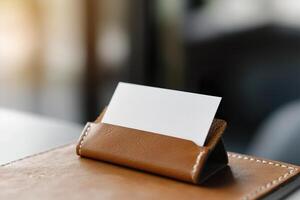 A blank business card is partially visible in a high-quality leather cardholder, resting on a desk with soft lighting creating an elegant atmosphere suitable for corporate branding photo