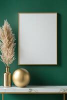 A stylish blank frame with a gold border hangs on a deep emerald wall, complemented by a marble console table below featuring a gold lamp and modern sculptures, creating a luxurious atmosphere photo