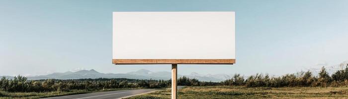 A large blank billboard stands alone on a tranquil country road. Lush green fields stretch out on either side, complementing the serene blue sky. Ideal for brands focused on nature and wellness photo