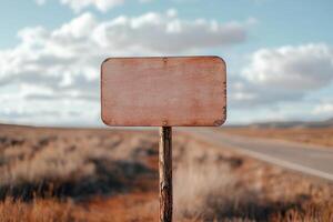 Blank signboard stands tall on a sturdy metal pole near a wide highway. Moving vehicles pass by against a backdrop of picturesque landscapes and a partly cloudy sky photo