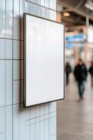 A sleek blank billboard mounted on a tiled wall is the focal point in a modern subway station, while commuters pass by, immersed in their daily routines. The soft blur adds to the urban atmosphere photo