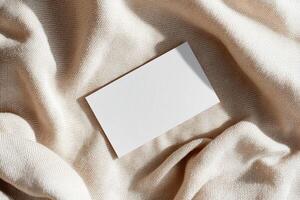 A blank business card rests on soft linen, showcasing gentle folds and shadows. The neutral background adds warmth, making it ideal for eco-friendly and boutique branding photo