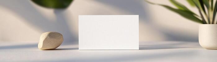 A blank business card lies flat on a white surface, softly illuminated by natural light. Subtle shadows add depth, creating a clean and professional aesthetic ideal for branding opportunities photo