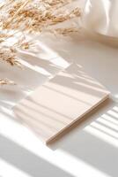 A blank business card rests flat on a white surface, illuminated by soft natural light. The subtle shadows and blurred background contribute to a clean and sophisticated atmosphere ideal for branding photo