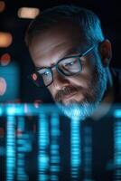 In a dimly lit office at night, a cybersecurity expert with glasses focuses intently on a glowing laptop screen, analyzing potential security threats and encrypted data photo