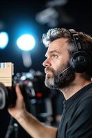 Director with headset holds a clapperboard, directing crew members on a busy film set. Bright studio lights illuminate the background, creating a cinematic atmosphere perfect for filmmaking photo