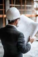 A professional architect in a suit and hard hat analyzes blueprints while engaging with colleagues at a bustling construction site featuring scaffolding and cranes in the background photo