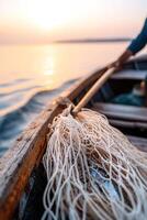 A fisherman skillfully pulls a net filled with fish from the water as the sun rises, casting a warm glow on the wooden boat and reflecting on the surface, creating a tranquil maritime atmosphere photo