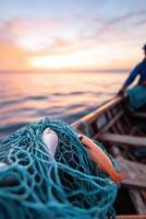A seasoned fisherman skillfully pulls in a net full of fish while the sun rises over the calm water. The serene backdrop features the vast ocean and distant shoreline in soft focus photo
