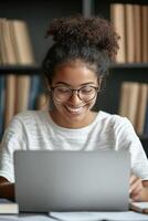 A cheerful tutor sits at her desk with an open laptop, effectively guiding a student through an engaging online lesson photo