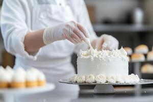 In a busy bakery kitchen, a skilled pastry chef in a white uniform meticulously pipes decorative frosting on a white cake while surrounded by trays of delicious pastries photo