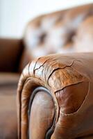 Focus on a close-up of an aged leather sofa with visible cracks and faded color. Soft lighting highlights its texture, ideal for vintage and rustic furniture restoration projects photo