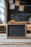 A rustic wooden-framed chalkboard sits on a desk, featuring softly drawn alphabet letters and a clear space for writing. The blurred classroom background adds an educational atmosphere photo