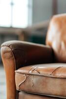 A vintage leather armchair reveals a layer of dust and cracks, highlighting its age and character. The soft-focus background adds depth, ideal for restoration insights photo