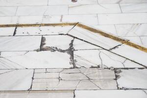 Cracked marble floor with a yellow line in an indoor space photo
