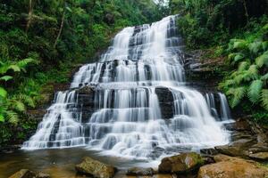 Scenic waterfall hidden paradise concept. A serene waterfall cascading over rocks surrounded by lush greenery. photo