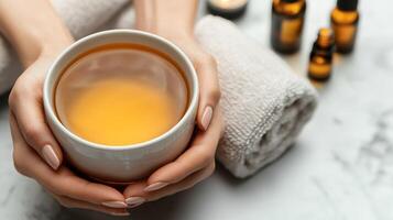 Relaxing spa self-care day concept. A person holds a bowl of warm liquid with towels and essential oils in the background. photo