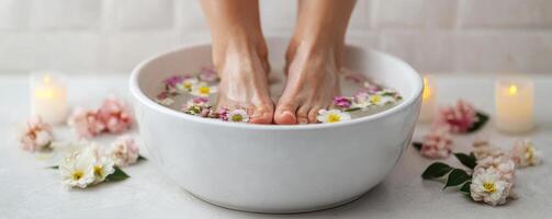 Relaxing spa self-care day concept. Relaxing feet soak with flowers in a bowl, surrounded by candles and floral decor. photo