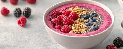 Healthy meal prep inspiration concept. Bright smoothie bowl topped with berries and granola on a textured surface. photo