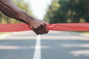 Achieving life goals determination concept. A hand holds a red ribbon across a deserted road, symbolizing a finish line or obstacle. photo