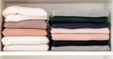 Ethical fashion sustainable materials concept. Neatly stacked sweaters in various colors displayed on a shelf. photo