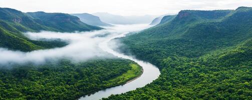 Exploring nature hidden gem concept. Lush green valley with a winding river and misty mountains in the background. photo