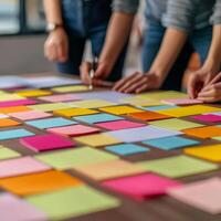 Startup brainstorming session concept. Hands arranging colorful sticky notes on a table in a collaborative workspace. photo