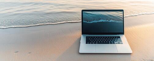 Digital nomad laptop beach. Laptop on a sandy beach beside gentle waves, symbolizing work-life balance and remote productivity. photo