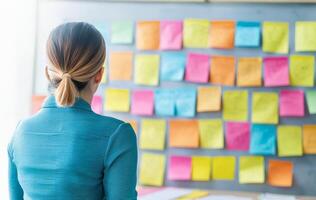 Startup brainstorming session concept. A person viewing colorful sticky notes on a wall, contemplating ideas or planning tasks. photo