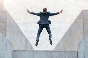 Inspirational success story motivation concept. A businessman jumps joyfully in a modern architectural setting. photo