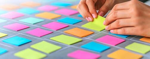 Project management coordination concept. Hands placing colorful sticky notes on a board for brainstorming or organizing ideas. photo