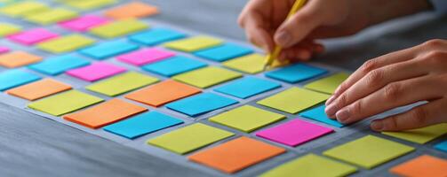 Project management coordination concept. Colorful sticky notes arranged on a surface with a person writing on one. photo
