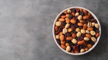 Nut trail mix with dried fruits concept. A bowl of mixed nuts and dried fruits on a textured gray background. photo