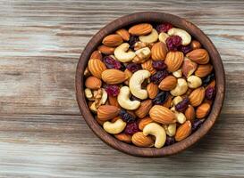 Nut trail mix with dried fruits concept. A wooden bowl filled with a variety of nuts and dried fruits on a rustic surface. photo