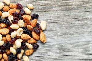Nut trail mix with dried fruits concept. Mix of nuts and dried fruits on a rustic wooden surface. photo