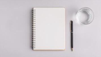 Wellness positivity and productivity concept. Blank notebook, pen, and glass of water on a textured surface for creative inspiration. photo