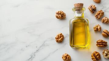 Walnut oil in glass bottle concept. Glass bottle of oil surrounded by walnuts on a marble surface. photo