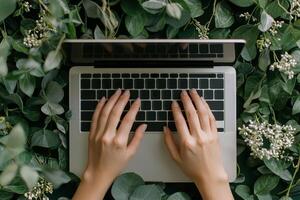 Wellness positivity and productivity concept. Hands typing on a laptop surrounded by greenery and flowers. photo