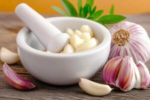 Garlic medicine and herbal remedy concept. Mortar and pestle with garlic cloves on a wooden surface, enhancing culinary visuals. photo