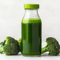 Broccoli juice in glass bottle concept. Fresh green juice in a bottle with broccoli surrounding it. photo