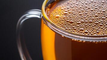 Mushroom tea in glass cup concept. Close-up of a glass mug filled with bubbly amber beverage. photo